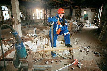 Image showing Woman wearing helmet using male work tools