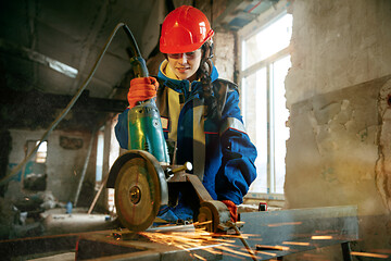 Image showing Woman wearing helmet using male work tools