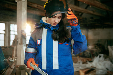 Image showing Woman wearing helmet using male work tools