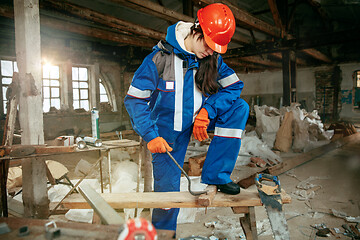 Image showing Woman wearing helmet using male work tools