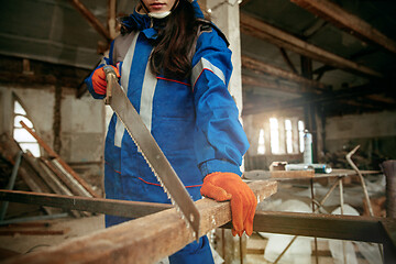 Image showing Woman wearing helmet using male work tools