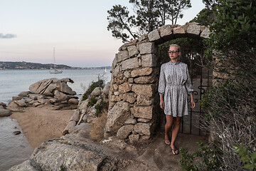 Image showing Beautiful woman in luxury summer dress enjoying peaceful seascape of Porto Rafael bay at Mediterranean sea of Costa Smeralda, Sardinia, Italy at dusk