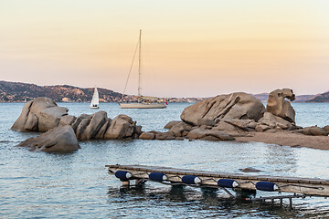 Image showing Sailboat sailing by beautiful rocky formations on the Spiaggia di Punta Nera beach. Luxury summer adventure, active vacation in Mediterranean sea, Costa Smeralda, Sardinia, Italy