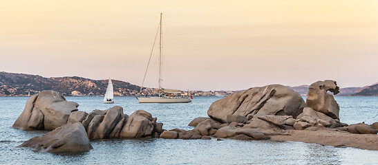 Image showing Sailboat sailing by beautiful rocky formations on the Spiaggia di Punta Nera beach. Luxury summer adventure, active vacation in Mediterranean sea, Costa Smeralda, Sardinia, Italy