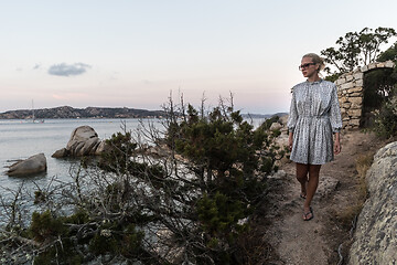 Image showing Beautiful woman in luxury summer dress enjoying peaceful seascape of Porto Rafael bay at Mediterranean sea of Costa Smeralda, Sardinia, Italy at dusk