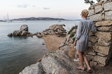 Image showing Beautiful woman in luxury summer dress enjoying peaceful seascape of Porto Rafael bay at Mediterranean sea of Costa Smeralda, Sardinia, Italy at dusk