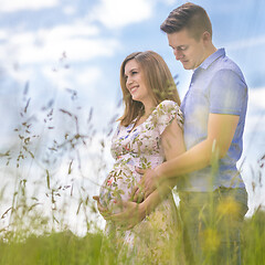 Image showing Young happy pregnant couple hugging in nature.