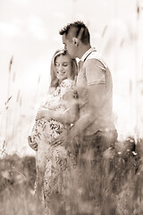 Image showing Young happy pregnant couple hugging in nature.