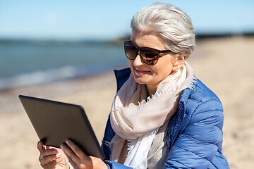 Image showing senior woman with tablet computer on beach