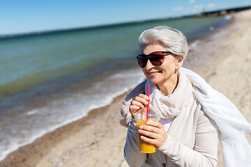 Image showing senior woman drinking orange juice on beach