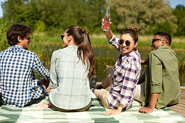 Image showing happy friends with drinks on lake pier in summer