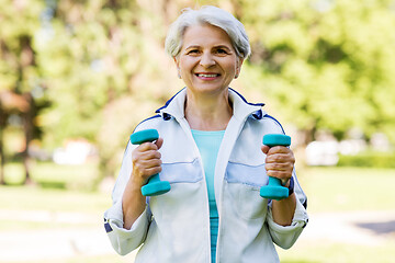 Image showing senior woman with dumbbells exercising at park