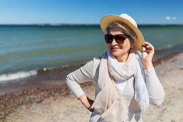 Image showing happy senior woman in sunglasses and hat on beach