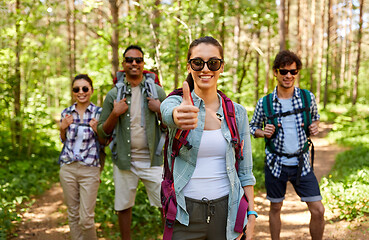 Image showing friends with backpacks showing thumbs up in forest