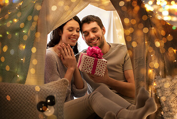Image showing happy couple with gift box in kids tent at home