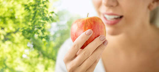 Image showing close up of woman eating ripe red apple in summer