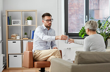 Image showing psychologist giving glass of water to senior woman