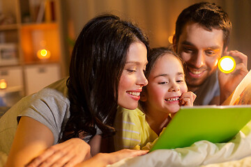 Image showing happy family reading book in bed at night at home