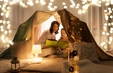 Image showing happy family reading book in kids tent at home