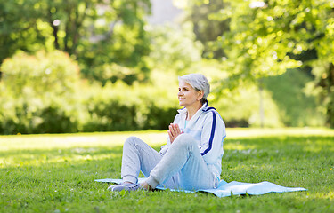 Image showing happy senior woman doing yoga at summer park