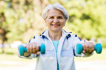 Image showing senior woman with dumbbells exercising at park