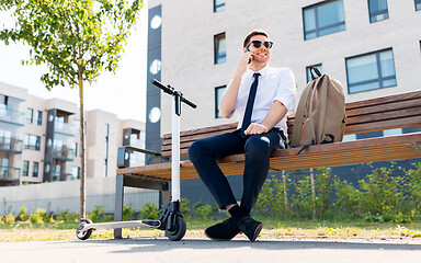 Image showing businessman with scooter calling on smartphone