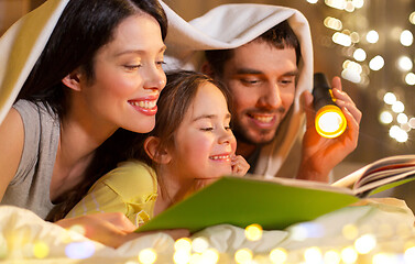 Image showing happy family reading book in bed at night at home