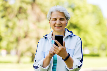 Image showing sporty senior woman with earphones and smartphone