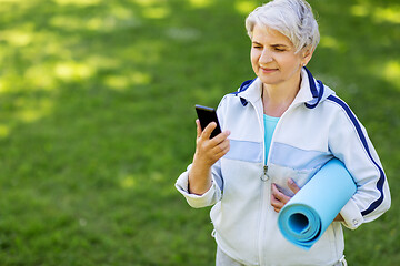 Image showing old woman with exercise mat and smartphone at park