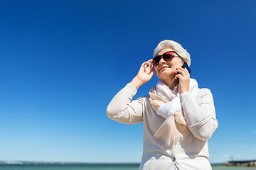 Image showing senior woman calling on smartphone on beach