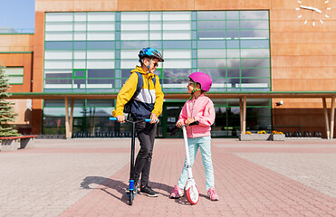 Image showing happy school children in helmets riding scooters