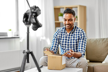 Image showing male video blogger opening parcel box at home