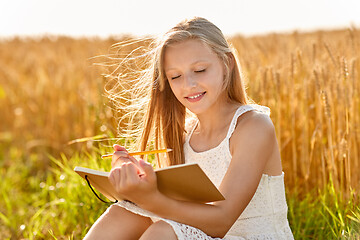 Image showing smiling girl writing to diary on cereal field