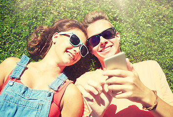 Image showing happy teenage couple smartphone lying on grass