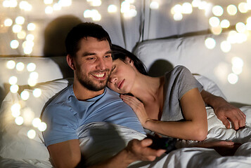 Image showing happy couple watching tv in bed at night at home