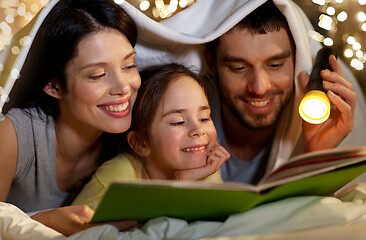 Image showing happy family reading book in bed at night at home