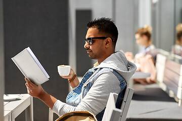 Image showing man reading book and drinking coffee at city cafe