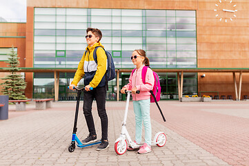 Image showing school children with backpacks riding scooters