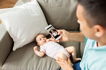 Image showing father with smartphone taking picture baby at home