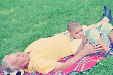 Image showing grandfather and child in park using tablet