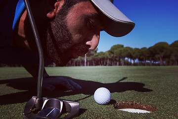 Image showing golf player blowing ball in hole