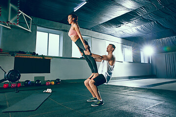 Image showing Shot of young man and a woman standing in plank position at the gym