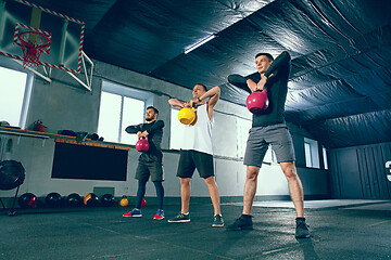 Image showing The strong young fitness men in sportswear doing exercises at gym