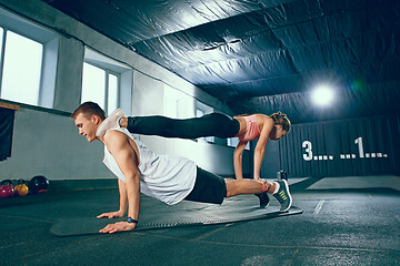 Image showing Shot of young man and a woman standing in plank position at the gym