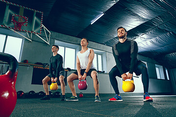 Image showing The strong young fitness men in sportswear doing exercises at gym