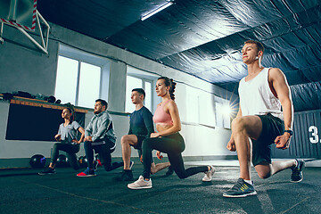 Image showing Shot of young men and a woman standing in plank position at the gym