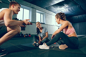 Image showing Portrait of young people resting and looking at camera after training session in gym.