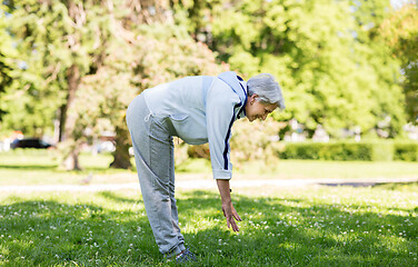 Image showing happy senior woman exercising at summer park