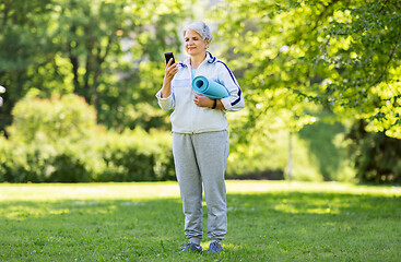 Image showing old woman with exercise mat and smartphone at park