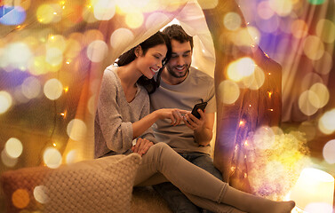 Image showing happy couple with smartphone in kids tent at home